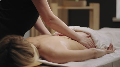 una mujer joven se relaja en el salón de masajes spa masajista está acariciando la espalda de la paciente relajación y placer