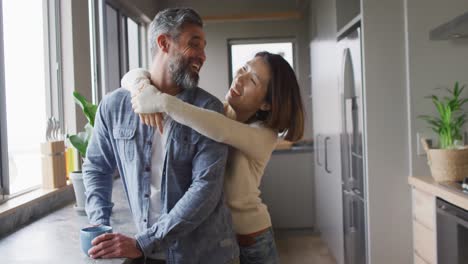 Feliz-Pareja-Diversa-Vistiendo-Ropa-Informal-Abrazándose-Juntos-En-La-Cocina