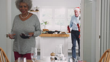 senior couple at home setting and decorating table for meal on christmas day