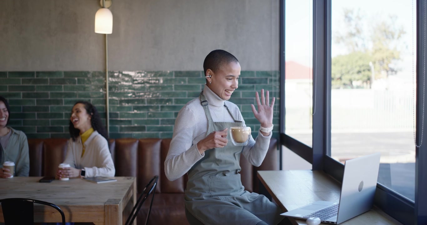 Woman African American barista joining laptop call gesturing sipping mug checking phone at counter