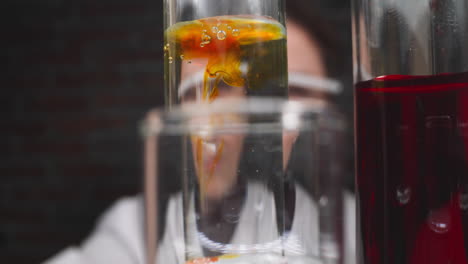 drops of orange chemical reagent fall down into test tube