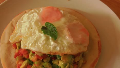 pita bread with avocado and tomatoes salad topped with fried egg for a healthy vegetarian breakfast