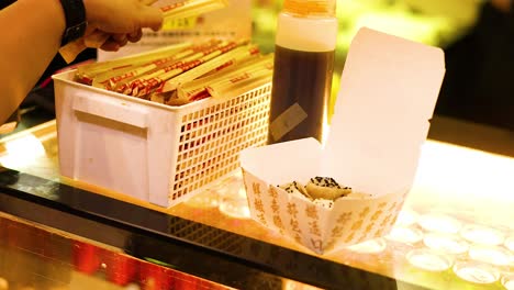 person selecting chopsticks at a food stall