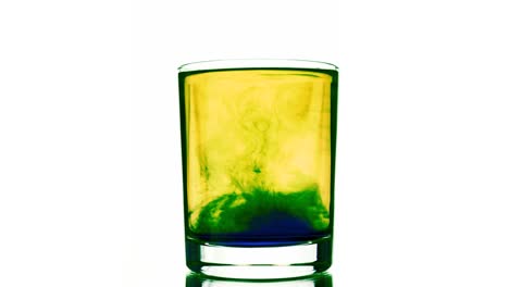 un pigmento azul líquido en movimiento disuelto en agua de color amarillo en vidrio sacudido