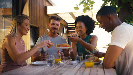 Gruppe-Lächelnder-Multikultureller-Freunde,-Die-Gemeinsam-Zu-Hause-Im-Freien-Frühstücken
