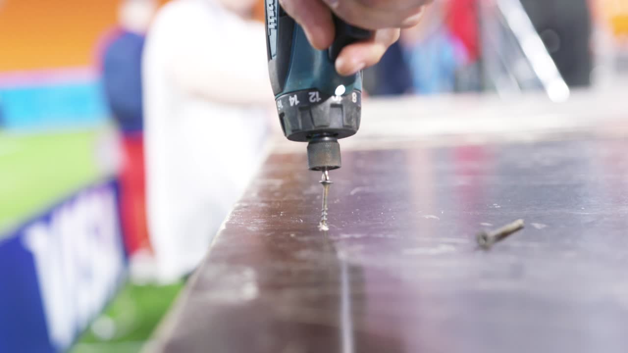 무언가를 조립하기 위해 드릴을 사용하는 사람