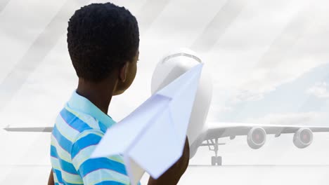 animation of african american boy playing with paper plane over silhouette of plane