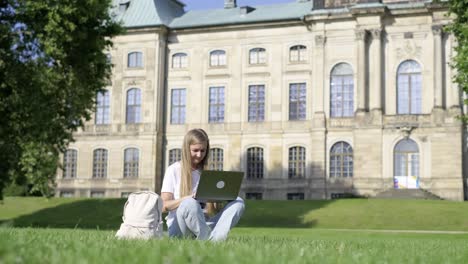 a woman working on her laptop on a university campus