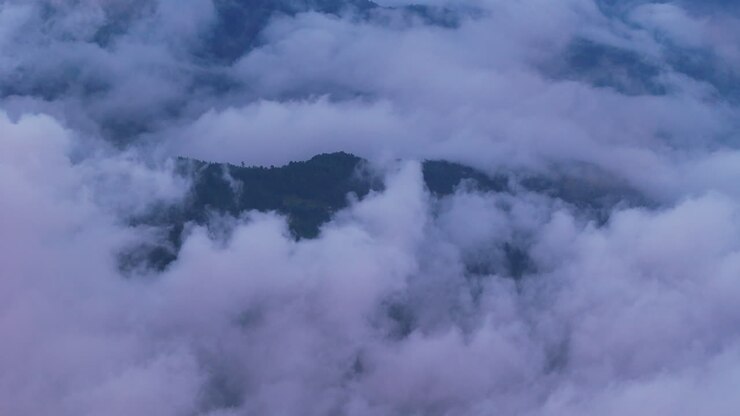 Breathtaking drone shot capturing clouds covering Nepal's hills under blue sky revealing astonishing and serene environment