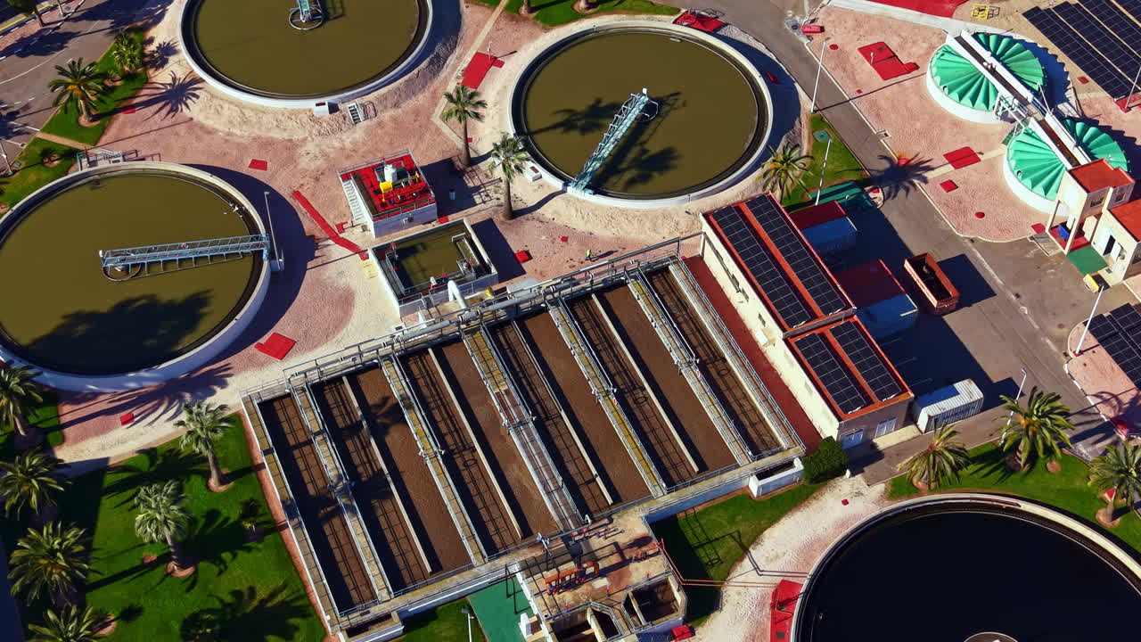 Water treatment facility operates with large tanks for cleaning water in a sunny location with green space around it