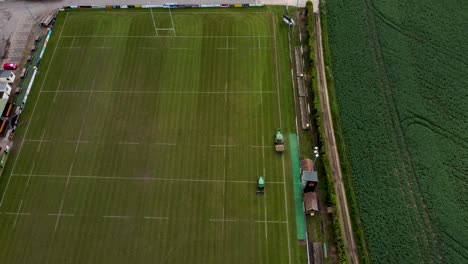 Disparo-De-Drones-De-Dos-Tractores-Cortando-El-Césped-En-El-Campo-De-Rugby-De-Canterbury