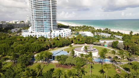 Park-on-a-white-sand-beach-and-rocky-port-with-palm-trees-blowing-in-the-wind-and-skyscrapers-on-the-coastline