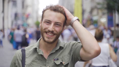 charming young man walking on crowded street looking at camera.