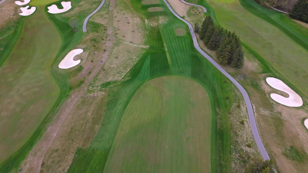Empty Green golf course with sand bunker in Canada. Aerial top down Flyover shot. Cloudy day in spring.