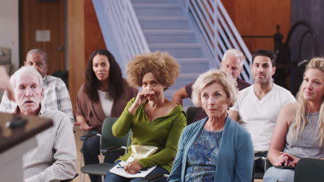 Group-Attending-Neighborhood-Meeting-Listening-To-Speaker-In-Community-Center