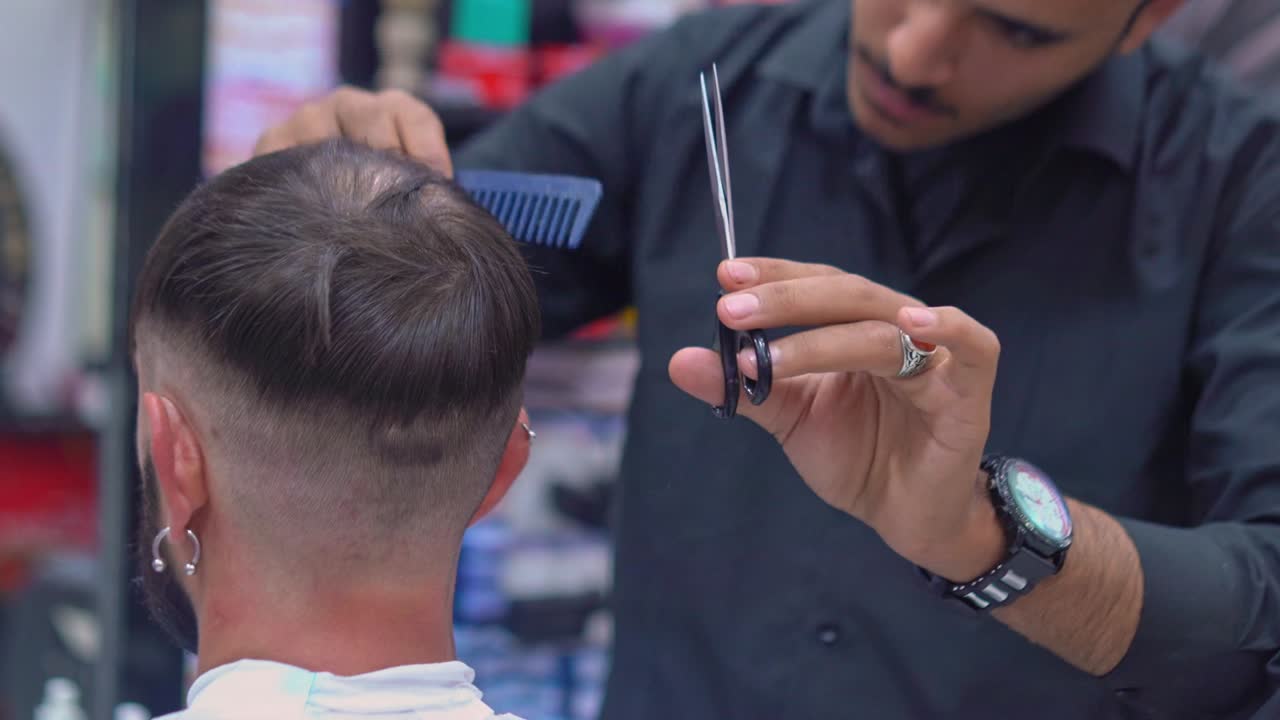 barbero corta el cabello de un hombre con tijeras en una barbería