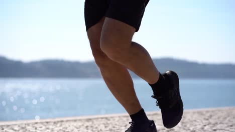 Low-section-if-man-in-shorts-and-sneakers-running-at-riverside