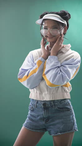vertical video: young woman in casual jacket laughing and holding sunglasses in studio