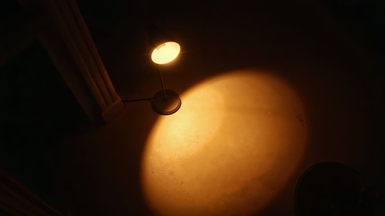 Lampada da scrivania con paralume inclinabile e panoramica della telecamera, luce circolare calda a terra che si sposta per uno studio di illuminazione.
