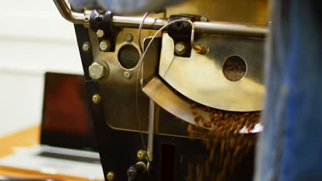 man using laptop while coffee grinding in machine