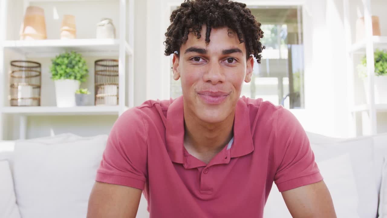 retrato de un hombre biracial feliz pasando tiempo en casa y haciendo una videollamada