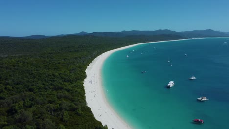 beautiful whitehaven beach with boats anchored near shore, tourist destination australia