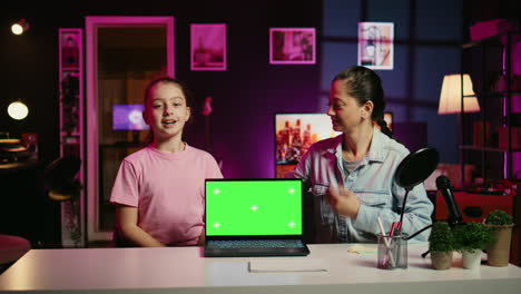 happy child and her loving mom recording green screen laptop review on online platforms