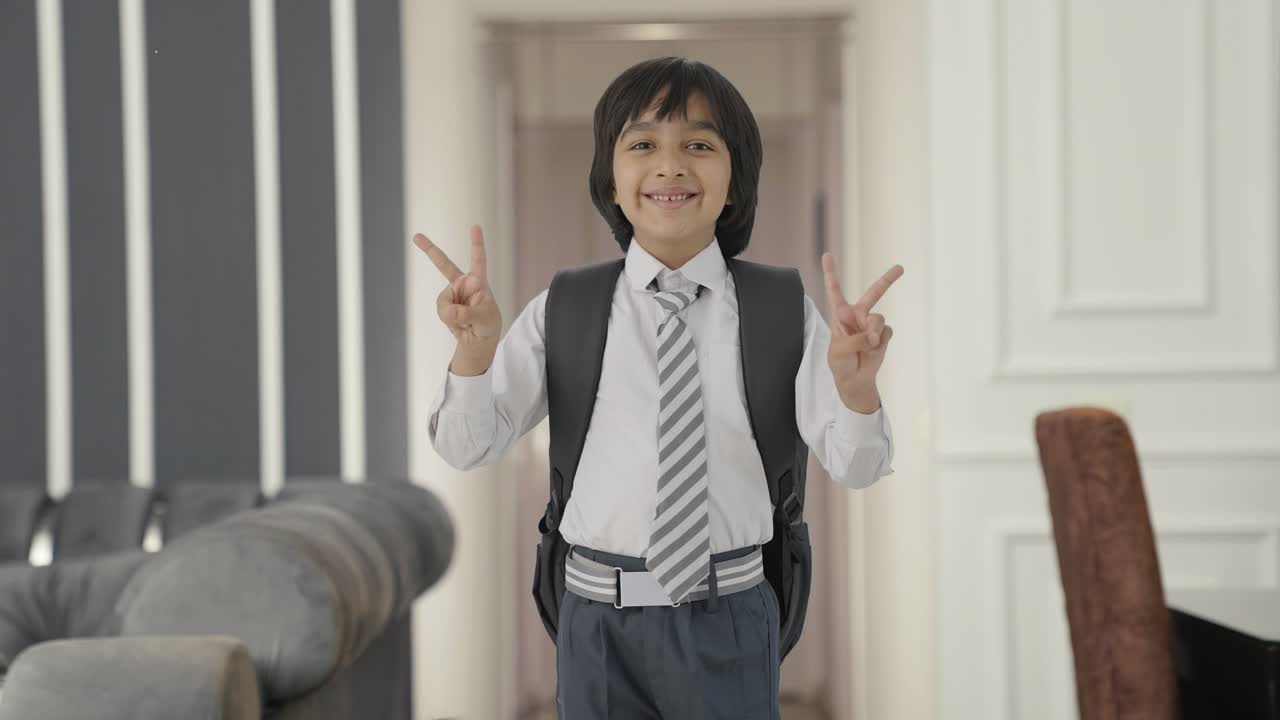 niño de escuela indio feliz mostrando el signo de la victoria