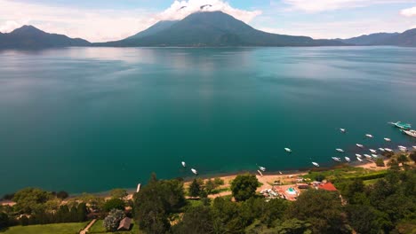 aerial lake and volcano pan up from coastline - lake atitlan, panajachel, guatemala