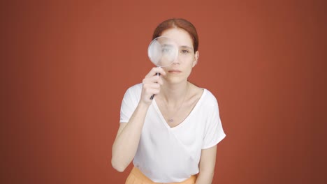 Woman-looking-at-camera-with-magnifying-glass.