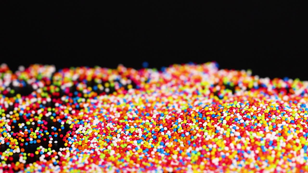 Vibrant sprinkles cascading against a dark background