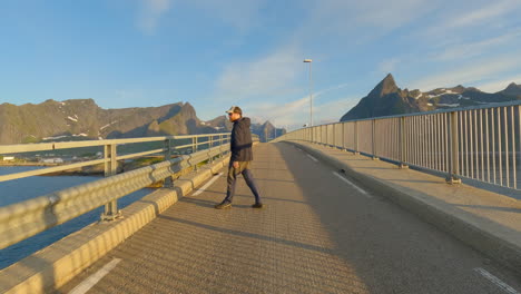 Young-male-enjoying-the-view-during-midnight-sun-on-Hamnoy-Bridge,-Lofoten-Island,-Norway