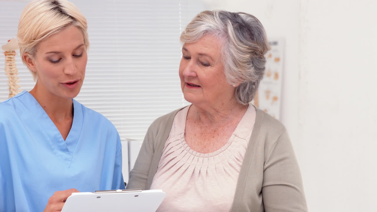 Nurse talking with elderly patient in office