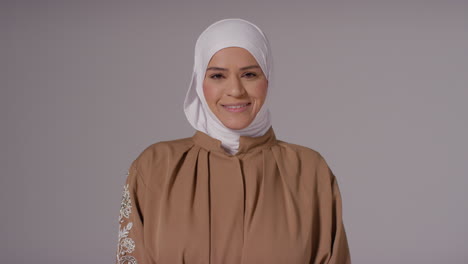 retrato de estudio de una mujer musulmana sonriente con hijab contra un fondo plano 4