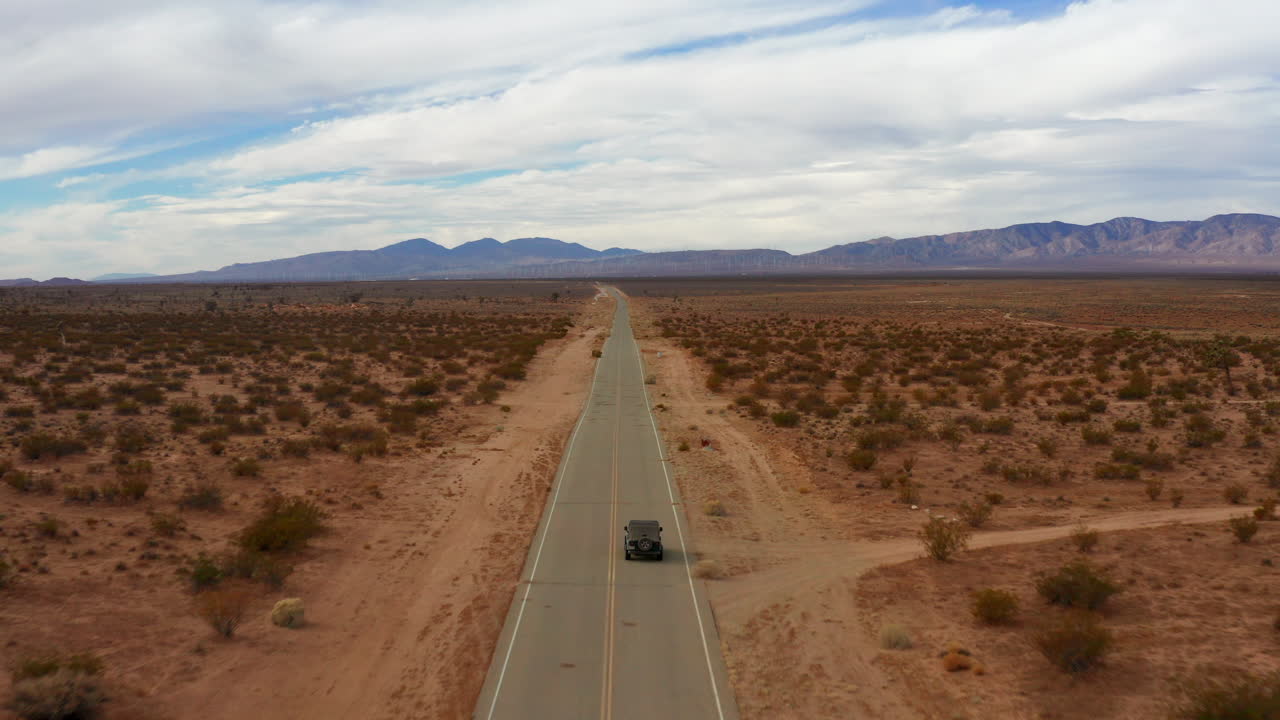 서사시 모하비 사막 풍경에서 고속도로에서 운전하는 지프 뒤에 공중, 비행
