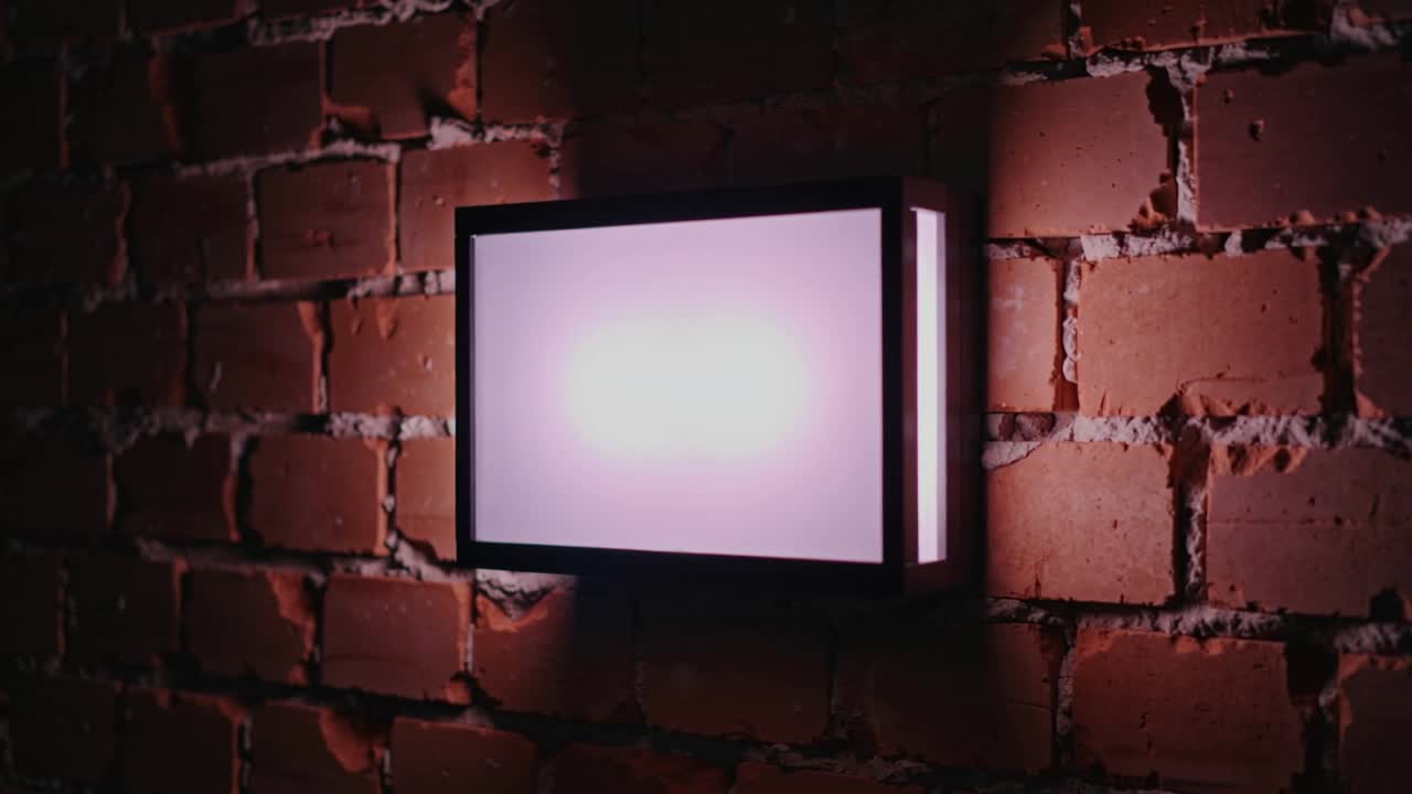 Luminaria que se ilumina extendiendo un resplandor, cámara ampliando en pared de ladrillo rojo, revelando el mortero.