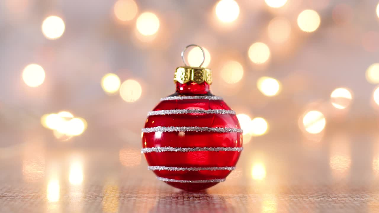 Riprese natalizie di una pallina ornamentale rossa lucida e luci di Natale intermittenti.