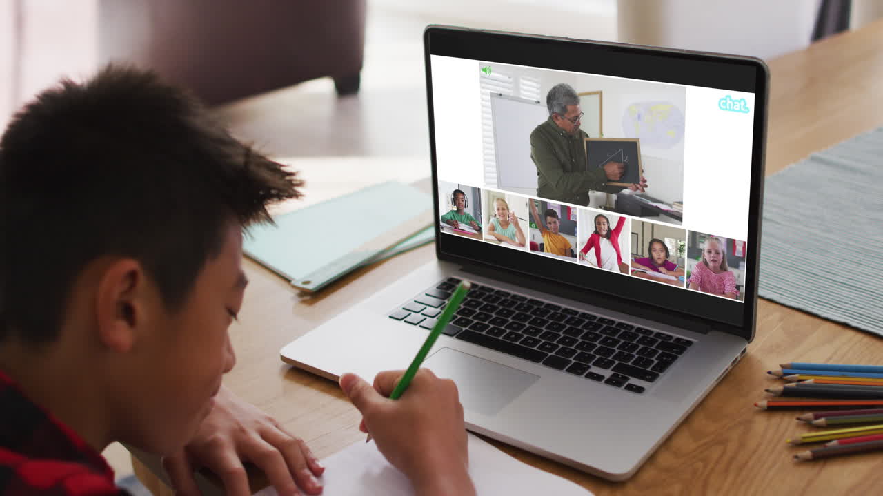 niño asiático haciendo la tarea y teniendo una videoconferencia con el maestro y sus compañeros de clase en la computadora portátil en casa