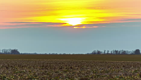 Tiro-Estático-De-Campo-Agrícola-Marrón-Con-Puesta-De-Sol-En-El-Fondo-En-Un-Día-Nublado-En-Timelapse