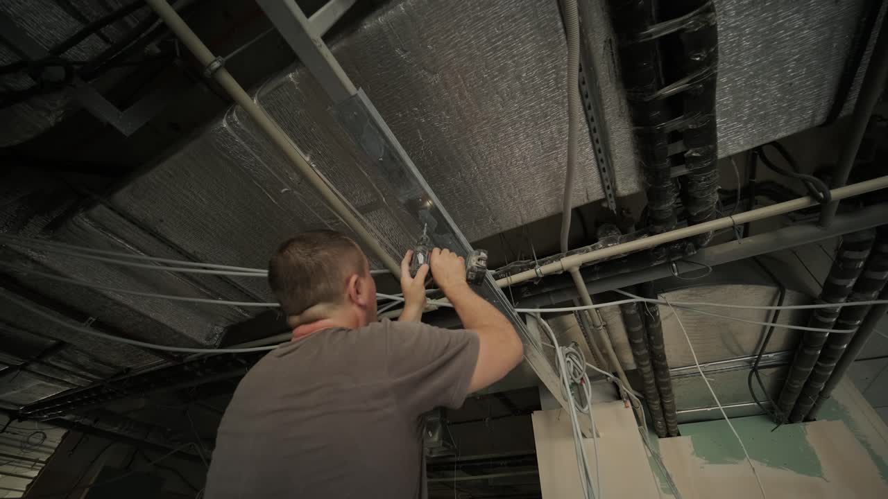 trabajador de la construcción ensamblar un techo suspendido con drywall y fijar el drywall al marco metálico del techo con destornillador. renovación, construcción y hazlo tú mismo concepto diy.