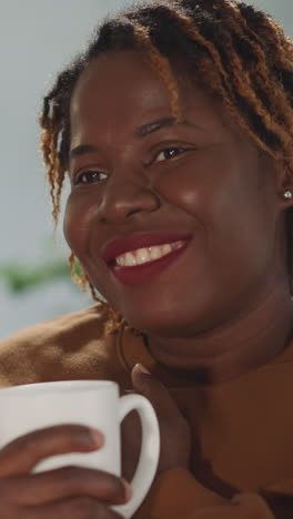 african american woman with dyed hair smiles touched by romantic movie. happy female person enjoys watching tv at home after work close view