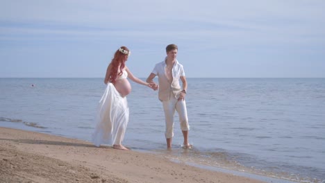 Love-couple-having-fun-on-sea-beach.-Pregnant-couple-splashing-water