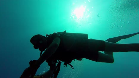 Shape-of-a-scuba-diver-swimming-in-silhouette-with-contrasted-light-green-background-breathing-bubbles