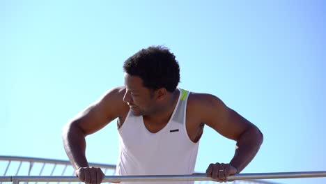 Muscular-man-doing-push-ups-on-bar-outdoor