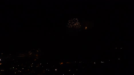 Celebration-with-colorful-and-sparkling-fireworks,-over-a-mountain-town,-at-night