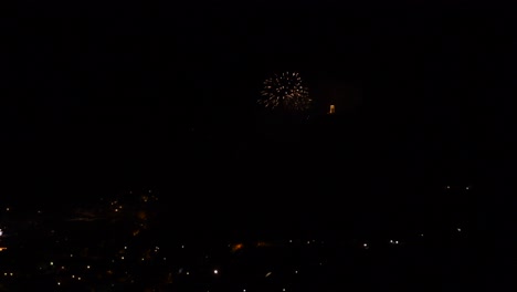 celebration with colorful and sparkling fireworks, over a mountain town, at night