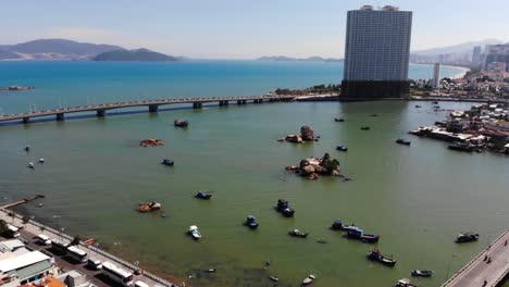 Drohnenansicht-Der-Küste-Von-Nha-Trang-Mit-Straßenbrücken-Und-Hohen-Stadtgebäuden-Im-Hintergrund-An-Sonnigen-Tagen-In-Vietnam