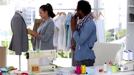 fashion designer on the phone while discussing with a colleague