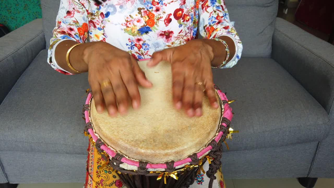 djembe 드럼을 연주하는 여자의 중간 폭 아래를 내려다 보면서 고립 된 샷