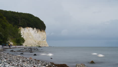 german people and tourists walk along white chalk cliffs on rugen island, traveling on pebble beach by baltic sea - timelapse motion